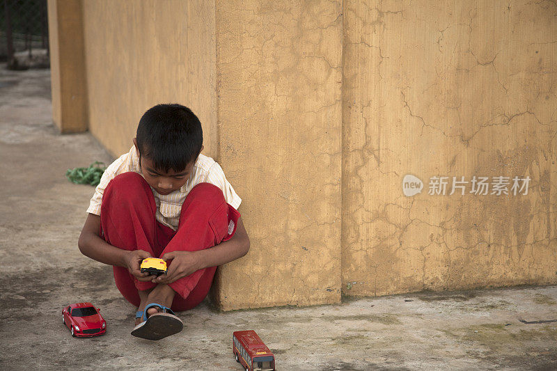 一个小男孩在印度城市的街道上玩玩具车。