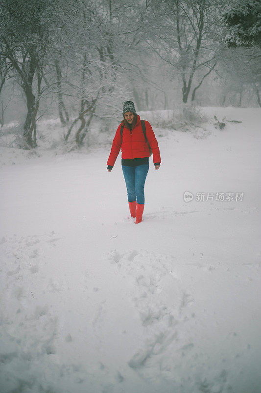 女徒步旅行者背包和雪鞋在雪地上的雪鞋