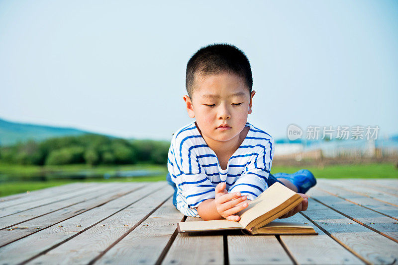 一个亚洲小男孩在大自然中读书