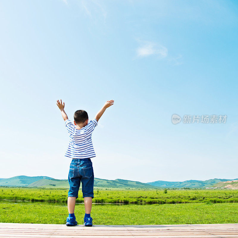 小男孩双手高举在户外