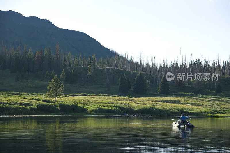 飞钓者在风景优美的高山湖上划船捕鱼