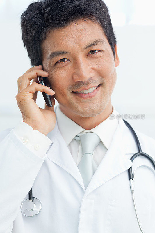 一个医生微笑着使用他的手机的特写