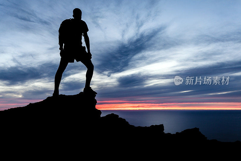 男人徒步剪影在山，海洋和日落