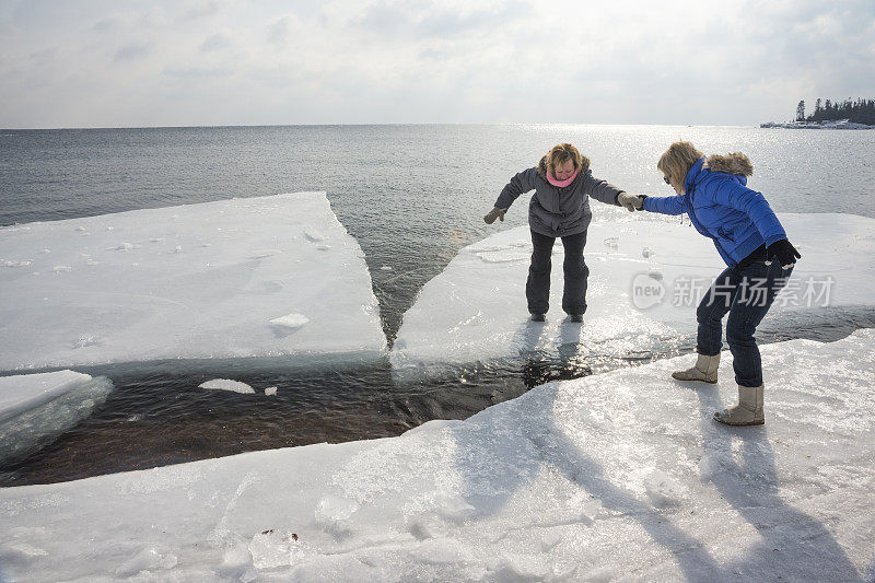 一名女子在冰上帮助另一名女子获救