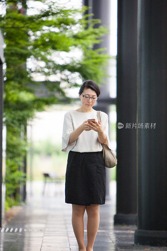 一名日本女商人正在研究她的智能手机