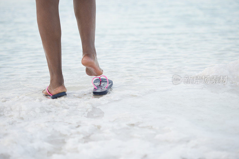 女游客在死海的咸海滩上的脚。