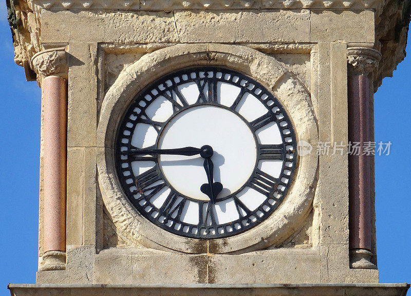 白色钟面的石头钟楼的形象，罗马数字