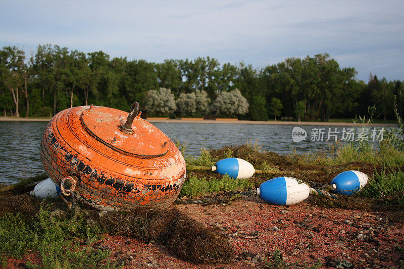 旧轮胎，橙色的浮标和蓝白色的标记在岸上