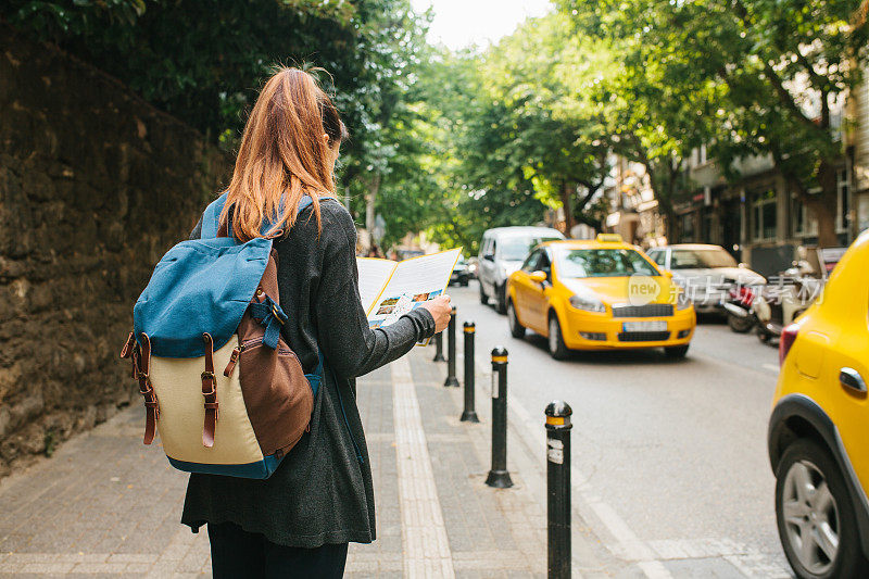 一个年轻的女游客背着背包在一个大城市里看地图。的旅程。观光。旅行。