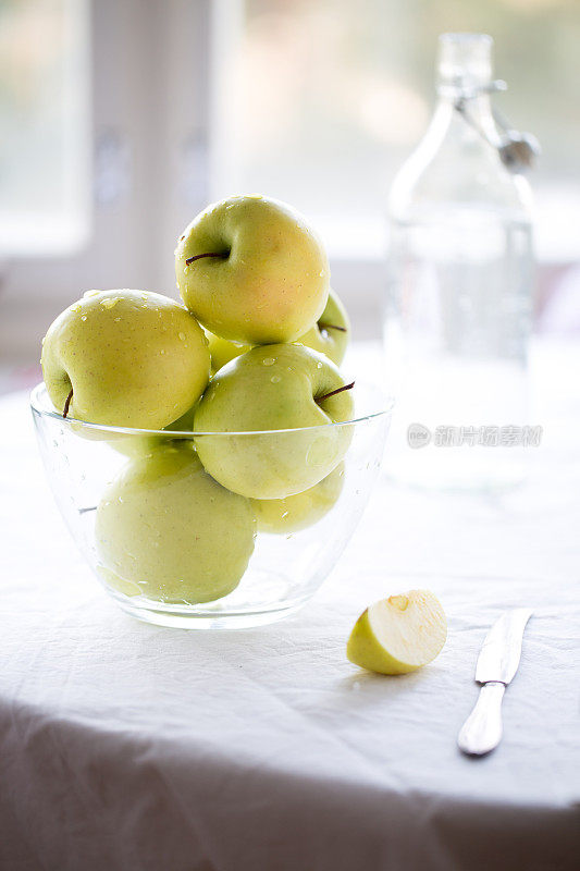 绿苹果放在一个大玻璃碗里，背景是白色