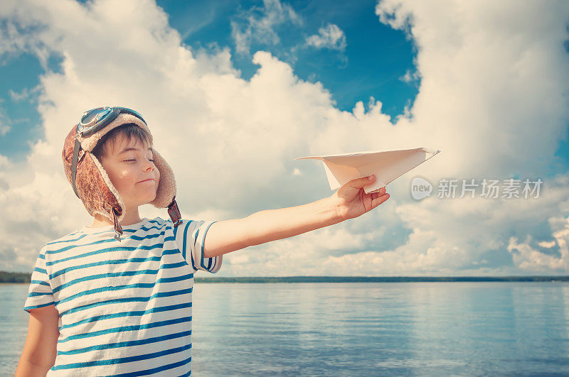 男孩戴着飞行员帽玩纸飞机