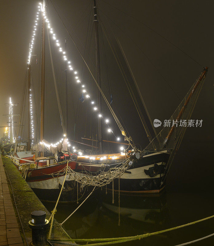 在一个雾蒙蒙的夜晚，古典帆船停泊在坎彭的码头上