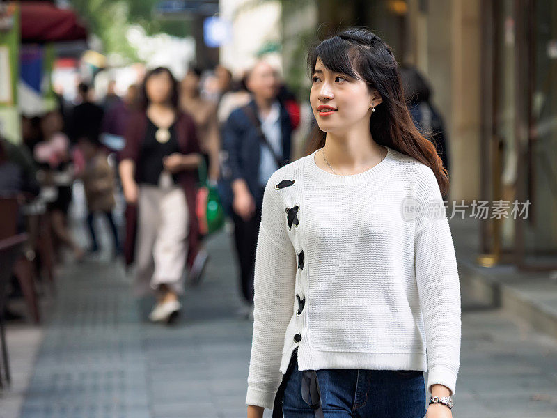 秋天的肖像快乐的中国女孩走在上海拥挤的街道上，中国。