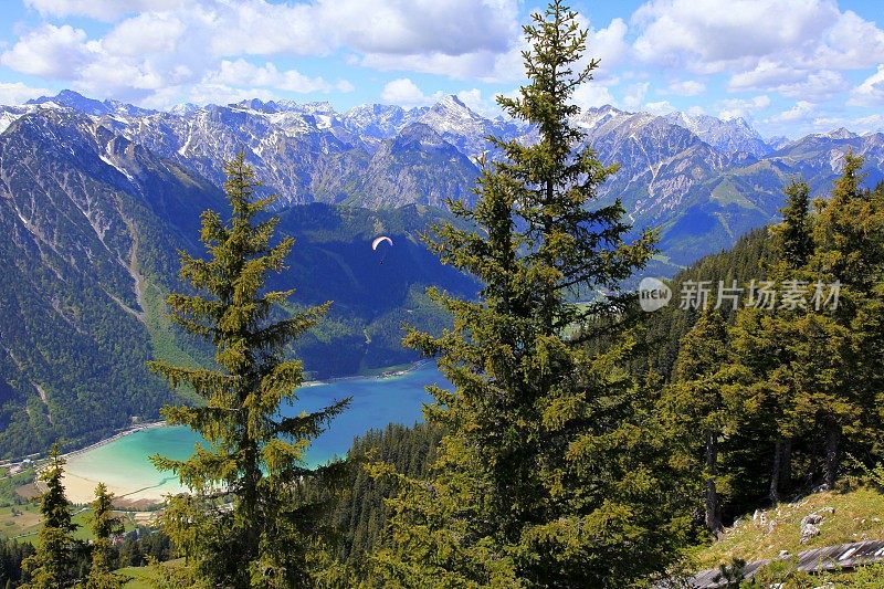 在松树之间的滑翔伞-在田诗式的阿钦斯绿松石湖反射，阿尔卑斯山景观在奥地利泰洛-卡温德尔山脉边界巴伐利亚阿尔卑斯-雄伟的高山景观，戏剧性的蒂洛尔雪山全景，奥地利