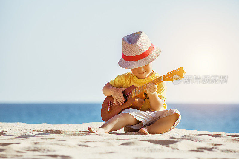 吉他尤克里里概念与小男孩在海滩
