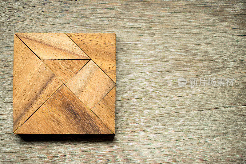 在木制背景上的方形七巧板拼图