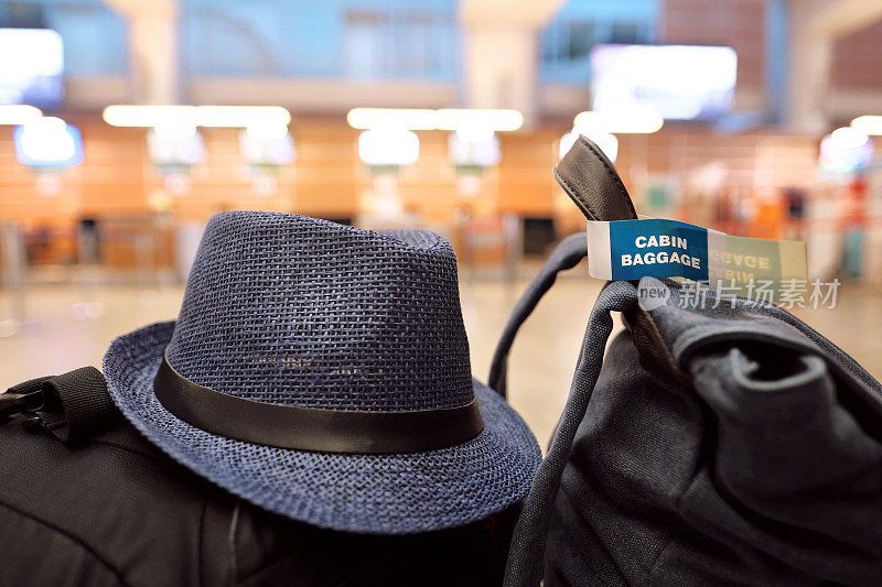 机场的长凳上放着手提行李和一顶旅客帽子