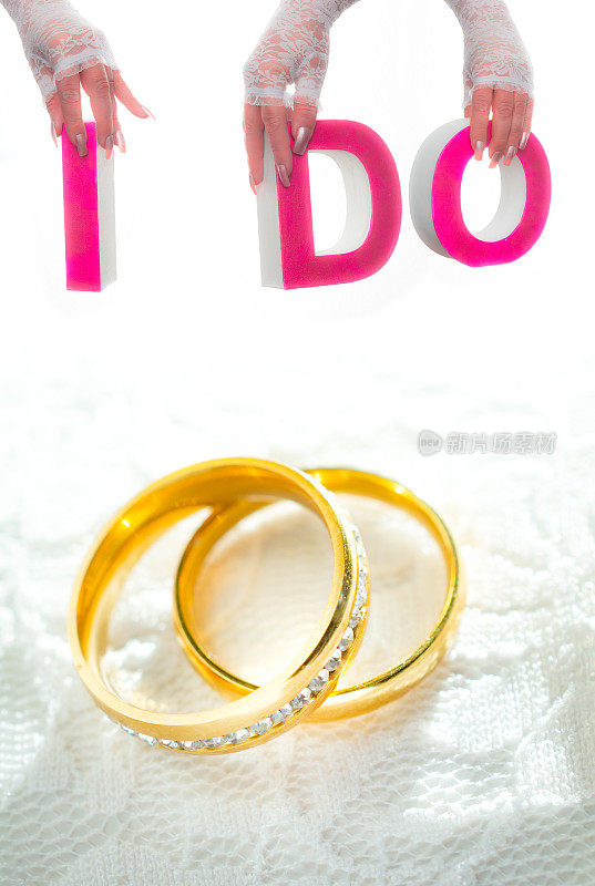 两个镶着花边的金戒指，新娘的手举着“我愿意”的字样