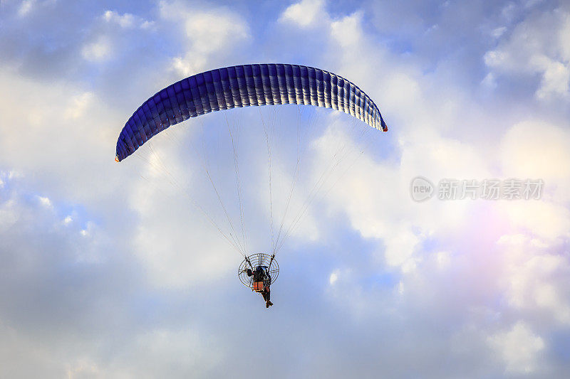 滑翔伞飞行在蓝色的阳光天空与云彩
