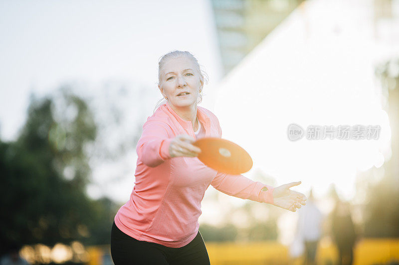 活跃的老年妇女在公园玩飞盘