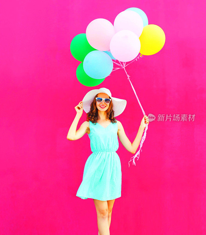 酷女孩拿着彩色气球走过粉红色的背景