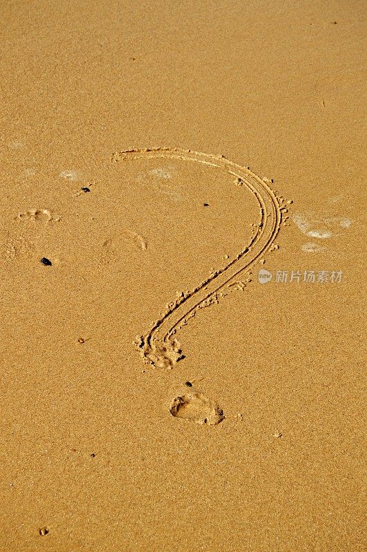 在一个阳光明媚的日子里，一个问号被写在沙滩上潮湿的沙子上