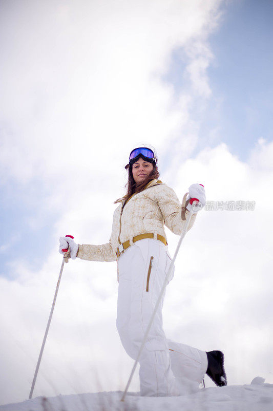 近景美丽的年轻女子在冬天的衣服站在一边，手拿木棍的背景雪山