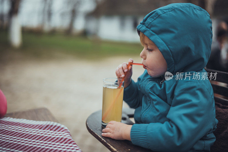 口渴的小男孩用吸管边喝边喝果汁。