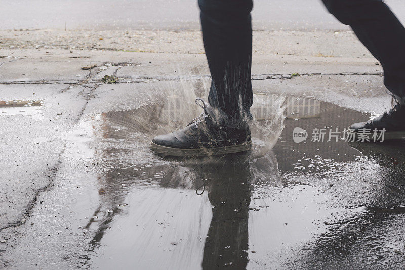 男脚踩进水坑，溅起了大水花