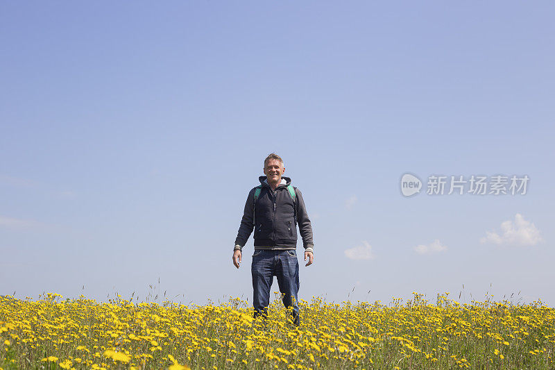 成年徒步旅行者喜欢在春天在美丽的花草地徒步旅行。