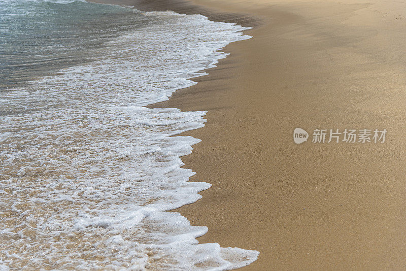 小波浪浸湿了海滩上的沙子