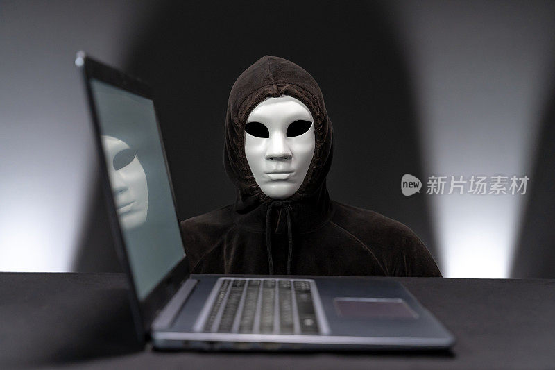 戴着面罩的电脑黑客盯着摄像头