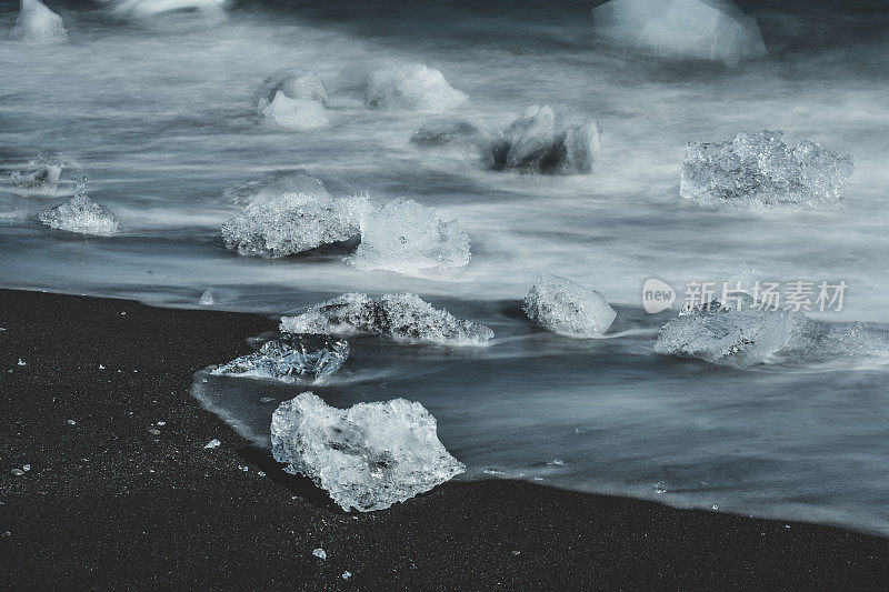 黑色的海滩上有冰块和海浪