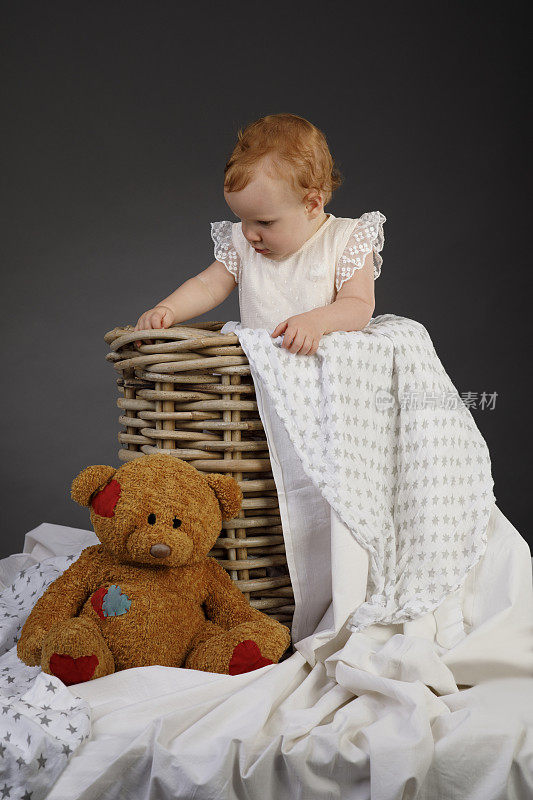 快乐宝贝肖像可爱的小女孩玩的玩具熊娃娃在篮子里