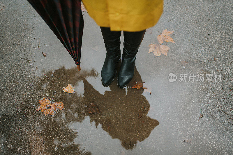 穿着黄色雨衣的年轻女子在公园里度过雨天
