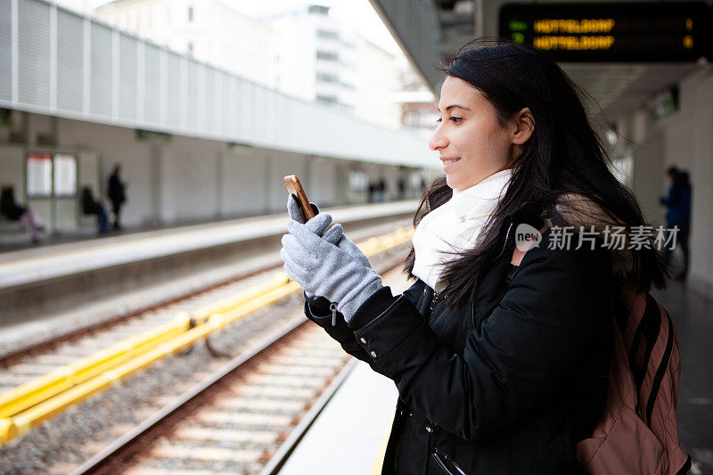 年轻女子在地铁站用手机储存照片