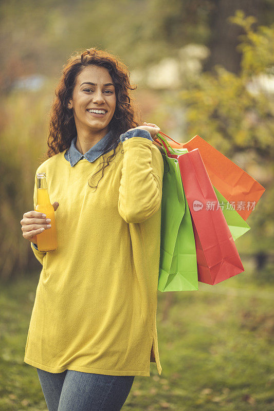 女人拿着购物袋喝橙汁的肖像