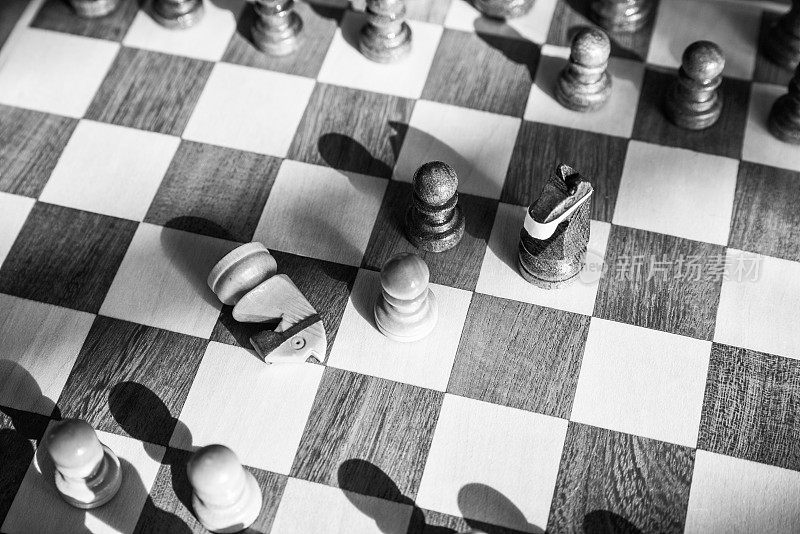 象棋中戴着防护面具的黑骑士在棋盘中间进攻，白骑士被击败