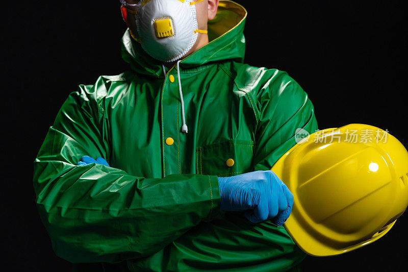 年轻的男工程师或工人的肖像，拿着他的头盔和显示拇指向上的标志在黑色的背景，特写