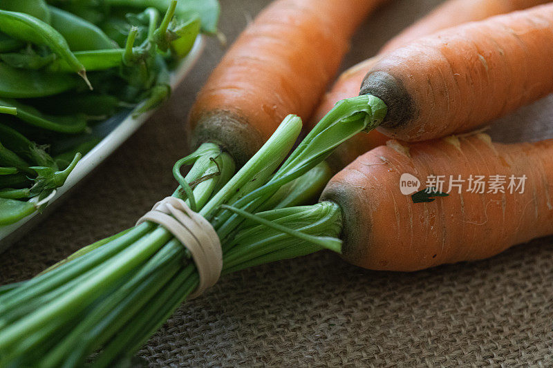 新鲜采摘的胡萝卜和雪豆的特写。