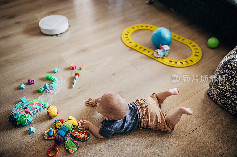 小男孩在玩玩具，机器人真空吸尘器在打扫地板