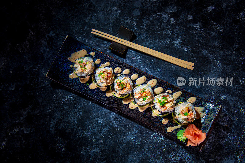 寿司盘正上方有寿司卷海苔，其余用筷子夹住