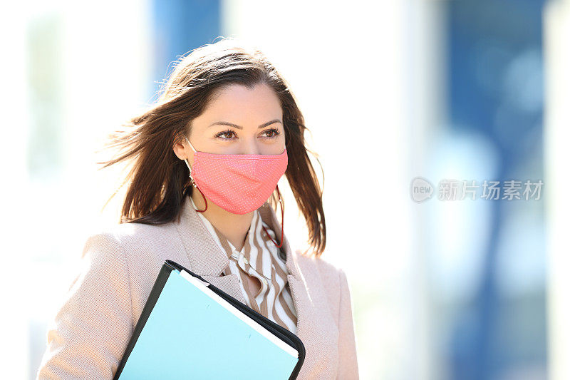 戴口罩的女商人在街上行走，以避免冠状病毒感染