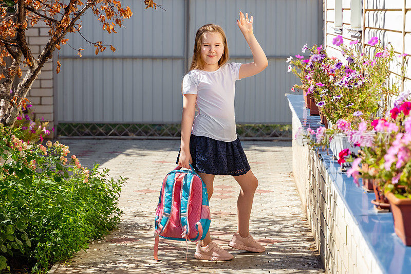 可爱的小女孩早上在外面，去上学，向妈妈挥手告别。