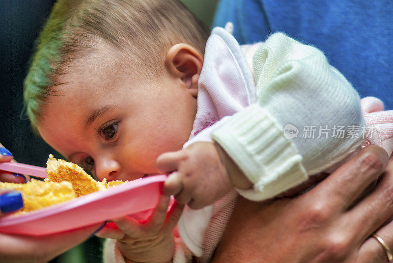 的童年。小婴儿试图从塑料盘子里吃东西