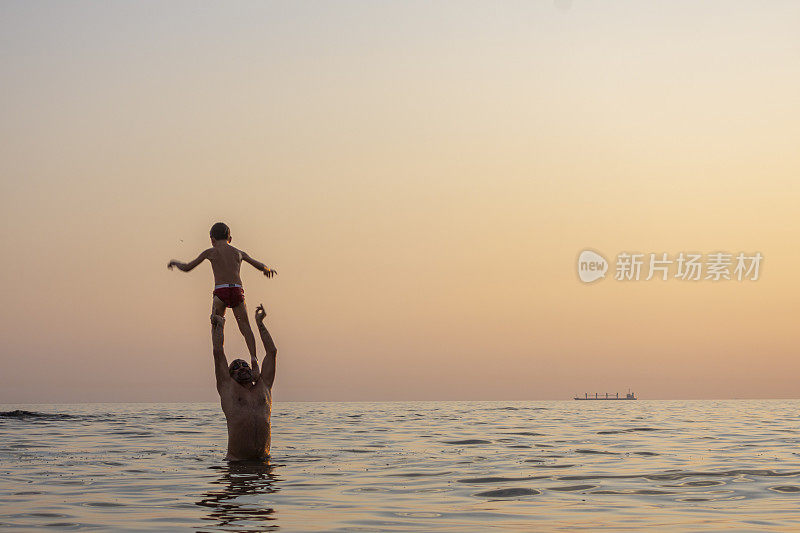 父亲抱着儿子的肩膀把他扔进海里