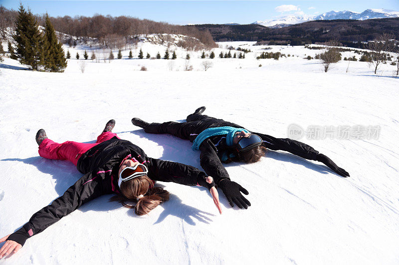 两个女孩躺在雪地上