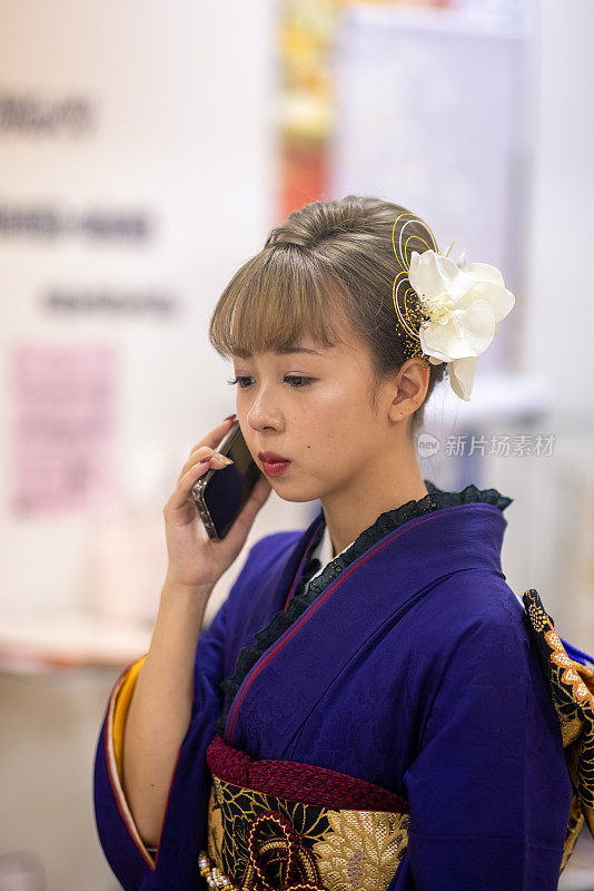 身着Furisode和服的年轻女子正在用智能手机聊天