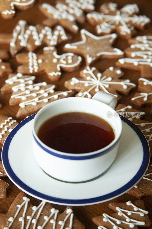 圣诞姜饼、星星、树、雪形饼干配一杯茶放在木桌上。