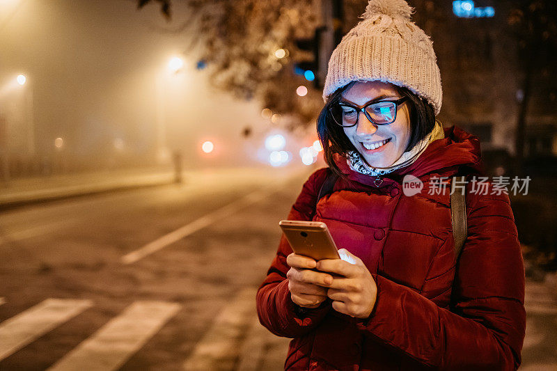 一个女人在雾霾的夜晚在街上打电话